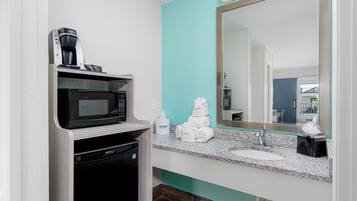 Une salle de bain moderne équipée d’un four à micro-ondes encastré, d’une machine à café et d’un lavabo avec un plan de travail en granit.