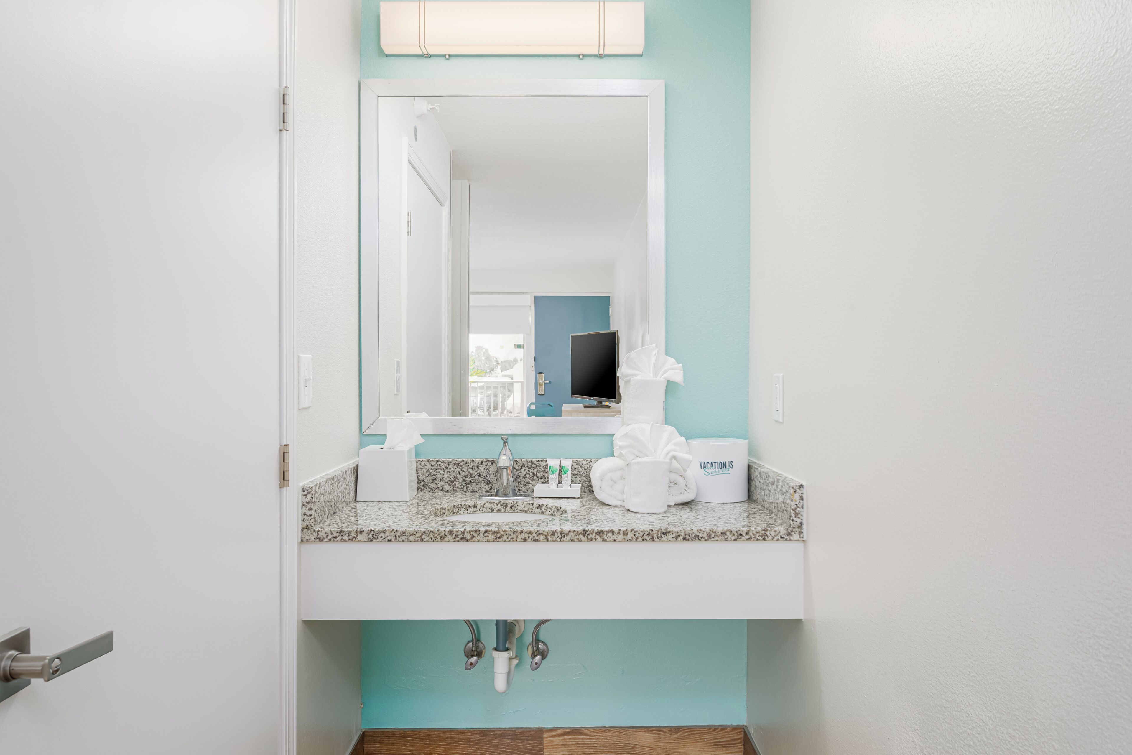 A bathroom with a white sink, a mirror, and a towel rack.