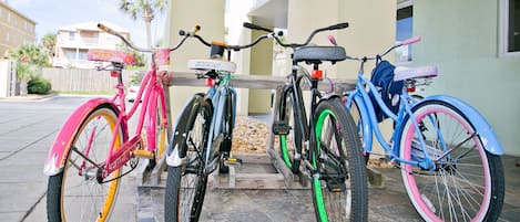 Tre cyklar parkerade framför en byggnad med en balkong.