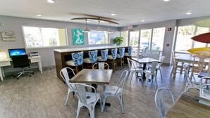 Un restaurante moderno con una zona de bar, sillas blancas y una mesa de madera.