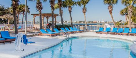A pool area with blue lounge chairs and palm trees.