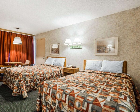 A hotel room with two beds, a desk, and a chair. There are wall-mounted lamps and framed pictures on the walls. - Econo Lodge Jefferson City (Jefferson City)