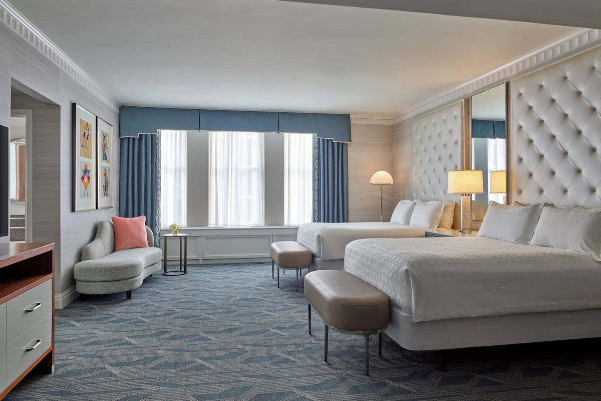 Una habitación de hotel con dos camas, un sofá, un escritorio y un espejo grande.