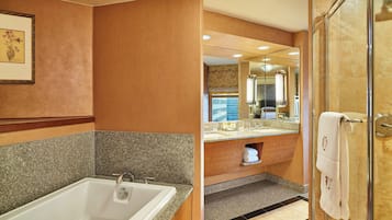 A modern bathroom with a large bathtub, a glass-enclosed shower, and a vanity with a mirror.