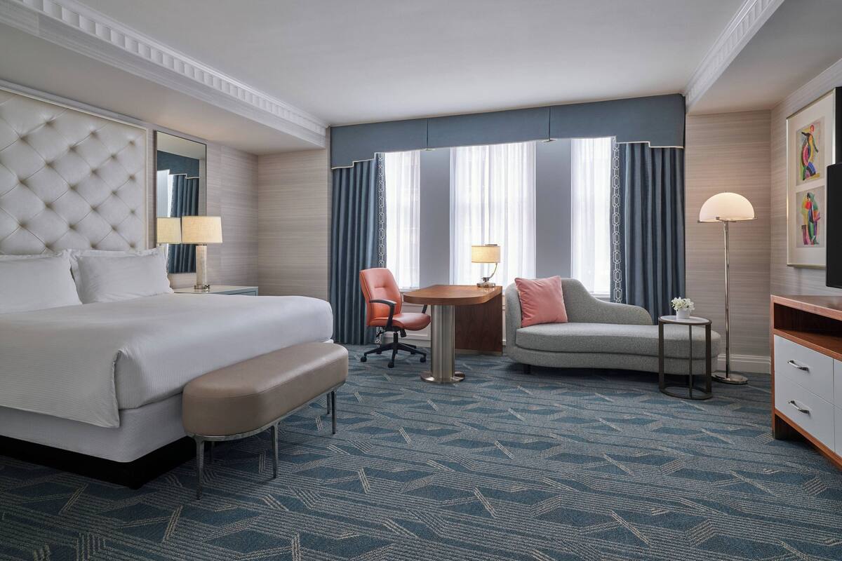 Una habitación de hotel con una cama grande, un escritorio, una silla y un sofá.