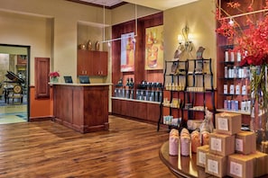 A reception area with a wooden desk, a computer, and a shelf with various products.
