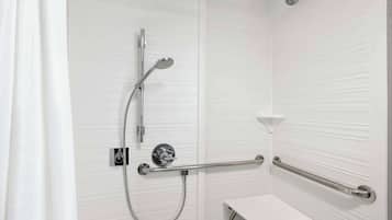 A shower area with a handheld showerhead, a wall-mounted faucet, and a grab bar.