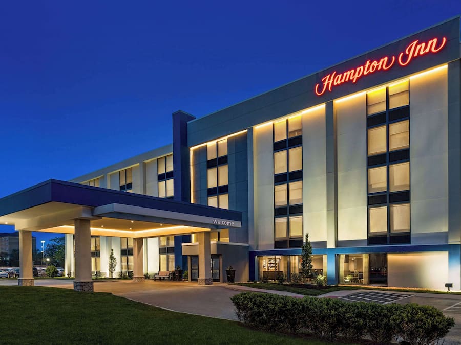 Un hotel Hampton Inn con fachada moderna, ventanas amplias y una entrada acogedora.