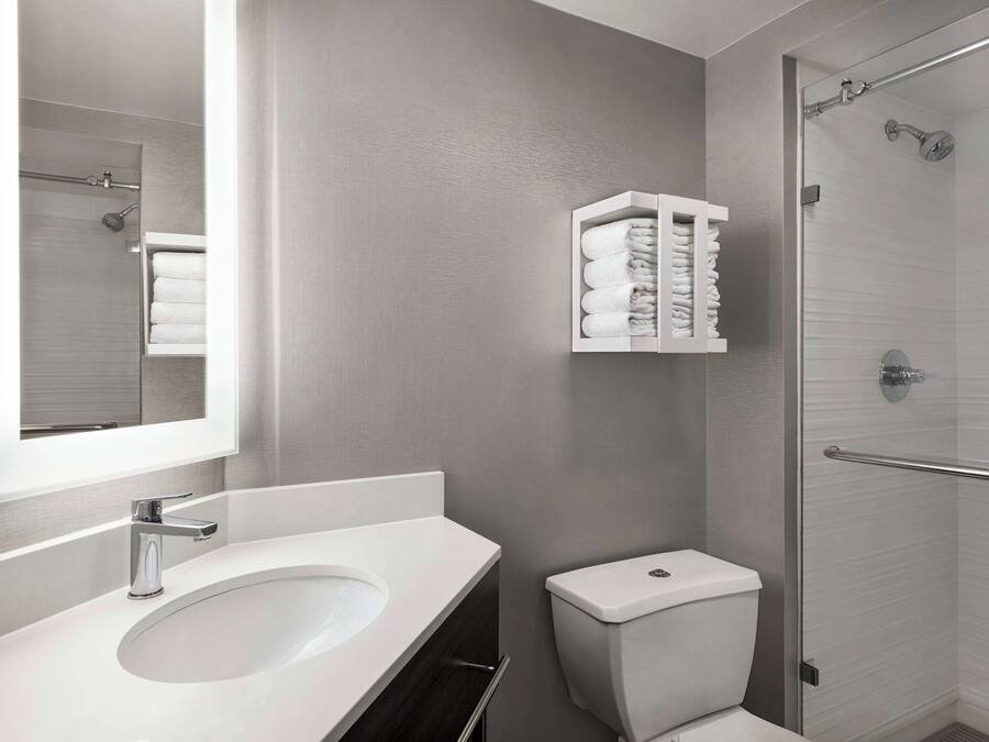 Un baño moderno con un lavamanos blanco, una cabina de ducha de vidrio y un perchero para toallas.