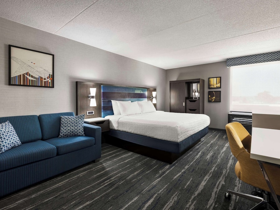 A hotel room with a bed, a sofa, a desk, and a large window.