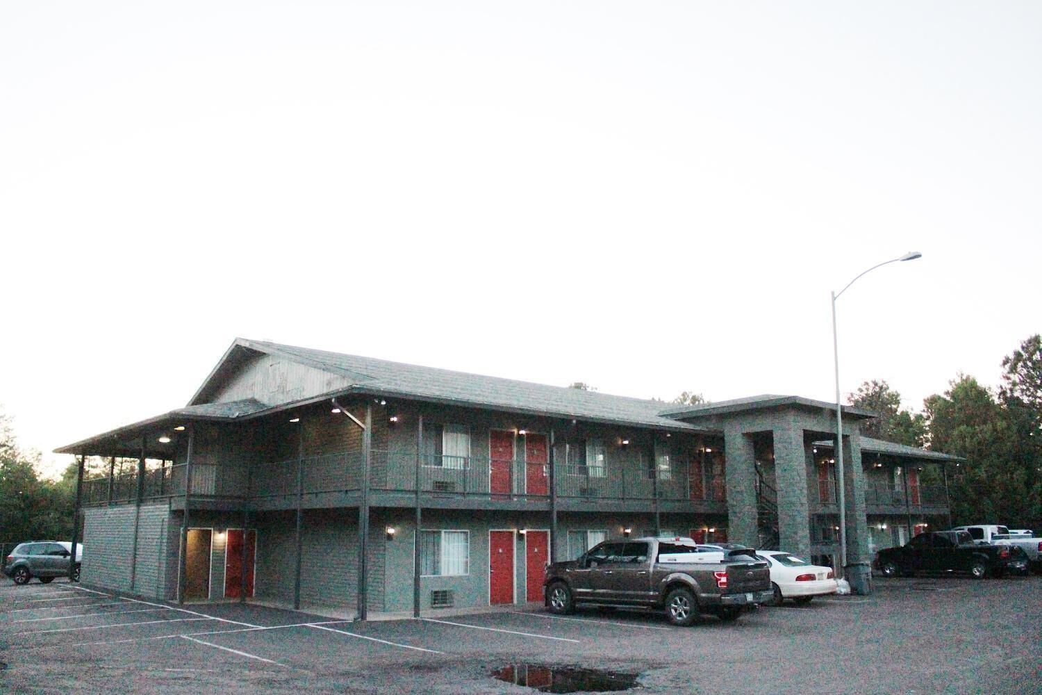 A motel with multiple rooms, a parking lot, and a streetlight.