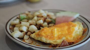 A breakfast plate with eggs, potatoes, and ham.