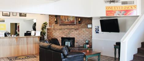 Amplia sala de estar con sofá de cuero, chimenea de ladrillo y televisor de pantalla plana montado en la pared.