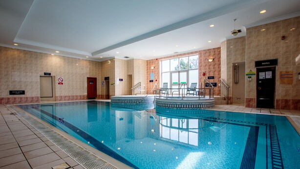 A large indoor swimming pool with clear water, surrounded by beige walls and a tiled floor. - The Aberdeen Altens Hotel (Aberdeen)