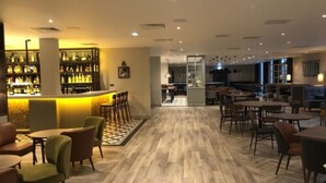 A spacious bar area with a long counter and multiple seating options including bar stools and tables. - The Aberdeen Altens Hotel (Aberdeen)