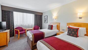 A hotel room with two beds, a TV, a desk, and a chair.