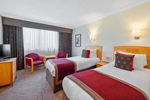 A hotel room with two beds, a TV, a desk, and a chair.