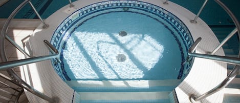Ein runder Pool mit gefliestem Rand und Metallgeländern.