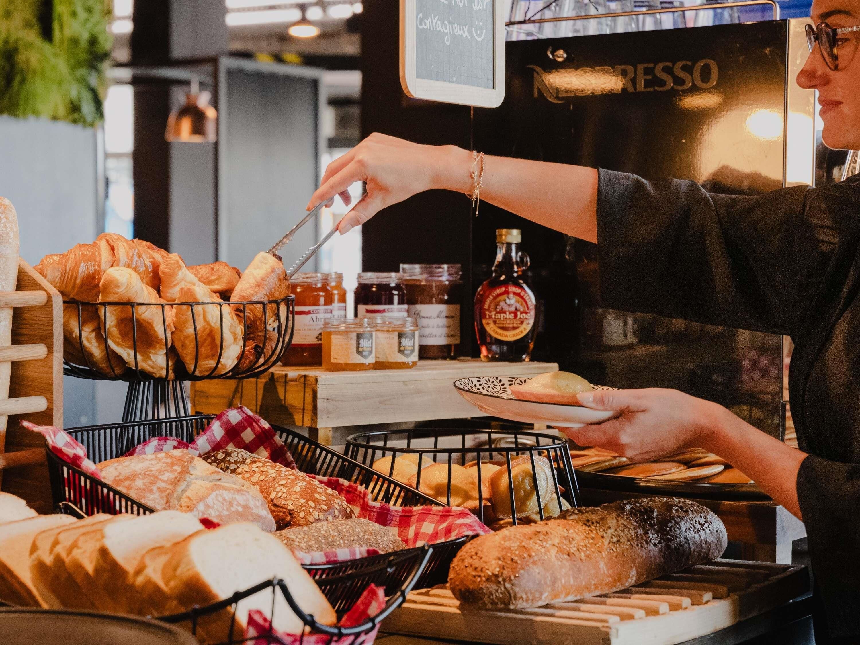 A bakery display with various breads and pastries, a coffee machine, and jars of condiments.