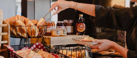 A bakery display with various breads and pastries, a coffee machine, and jars of condiments.