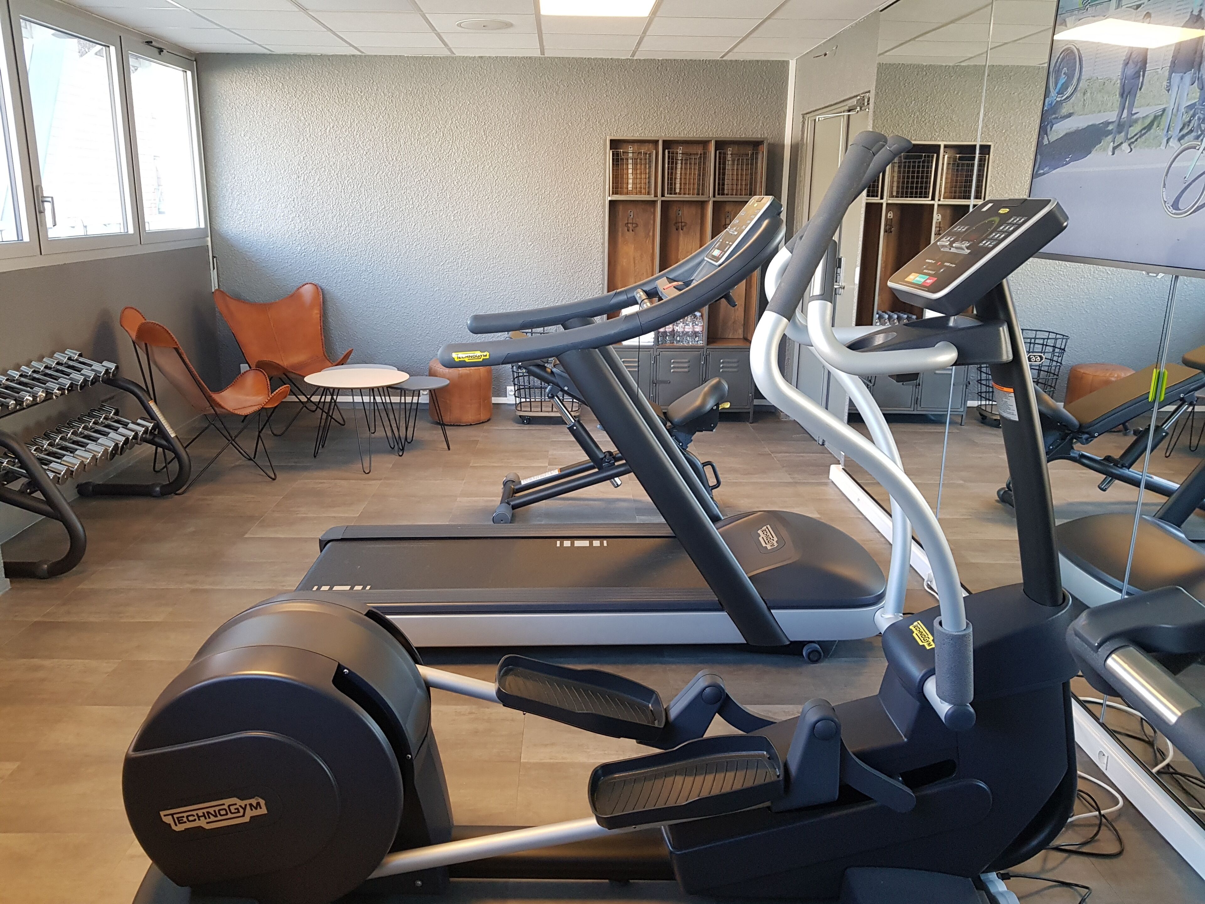 A gym with treadmills, weight machines, and a mirrored wall.