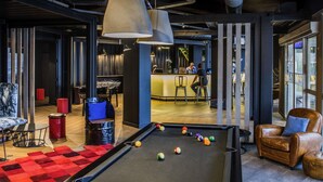 Une table de billard avec des billes, une table de jeu de pool et un coin bar avec des tabourets.