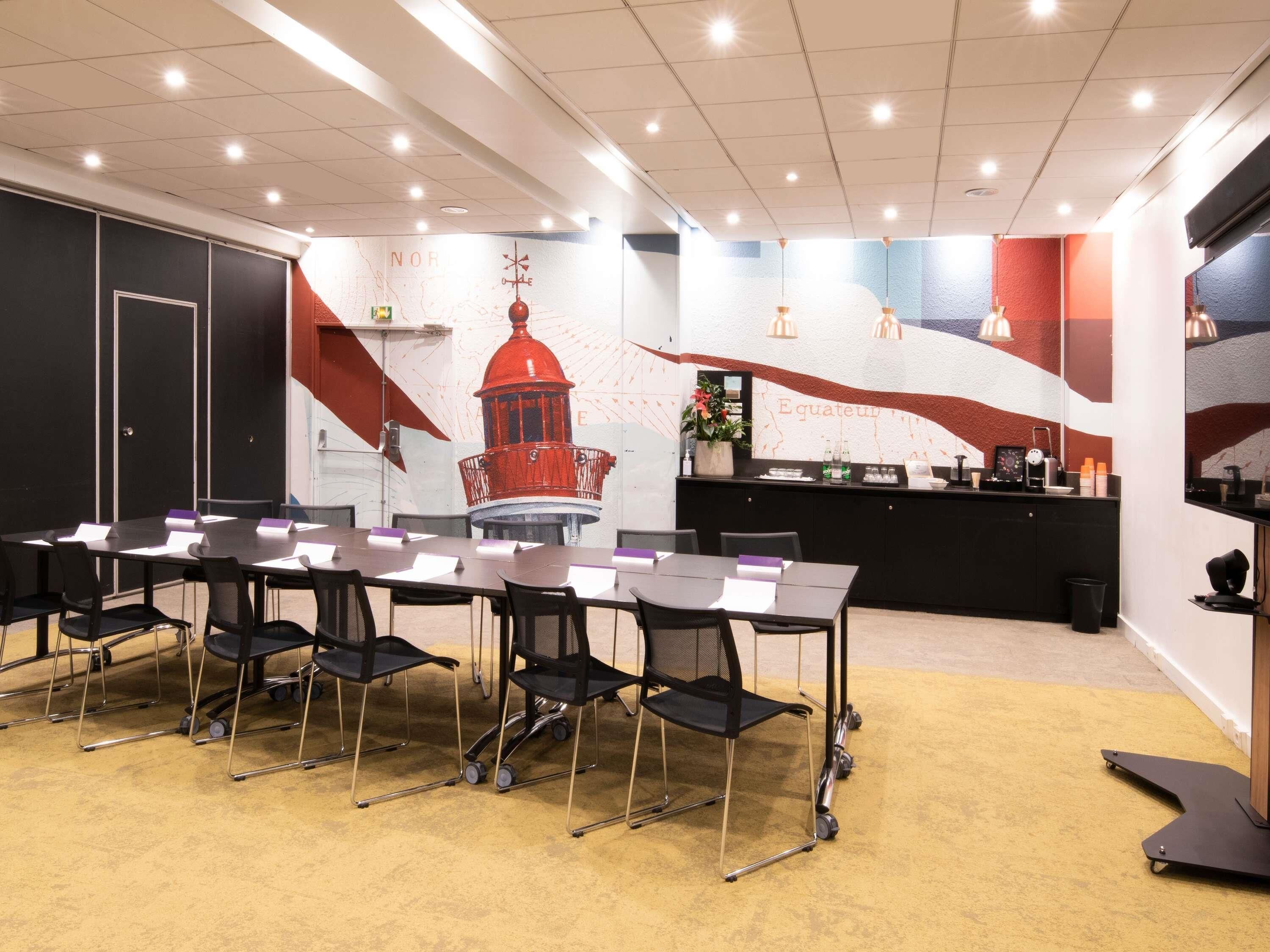 Un salón de conferencias con una mesa larga, sillas, un mapa en la pared y una barra con servicios.