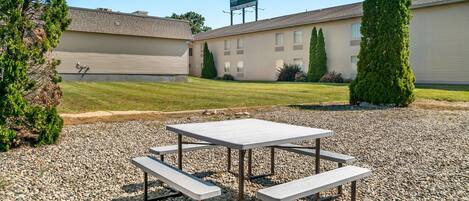 A picnic table with benches in front of a building with a sign that reads "Quality Hotel & Suites".