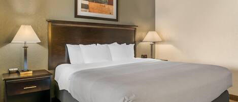 Una cama bien hecha con sábanas blancas, un cabecero de madera oscura y dos lámparas de noche.