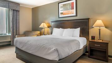 Camera d'albergo con un letto grande, due lampade ai comodini, un quadro appeso al muro e una finestra con tende.