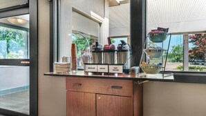 Un área de cocina moderna con un mueble de madera, un dispensador de agua de acero inoxidable y una ventana con vista a follaje.