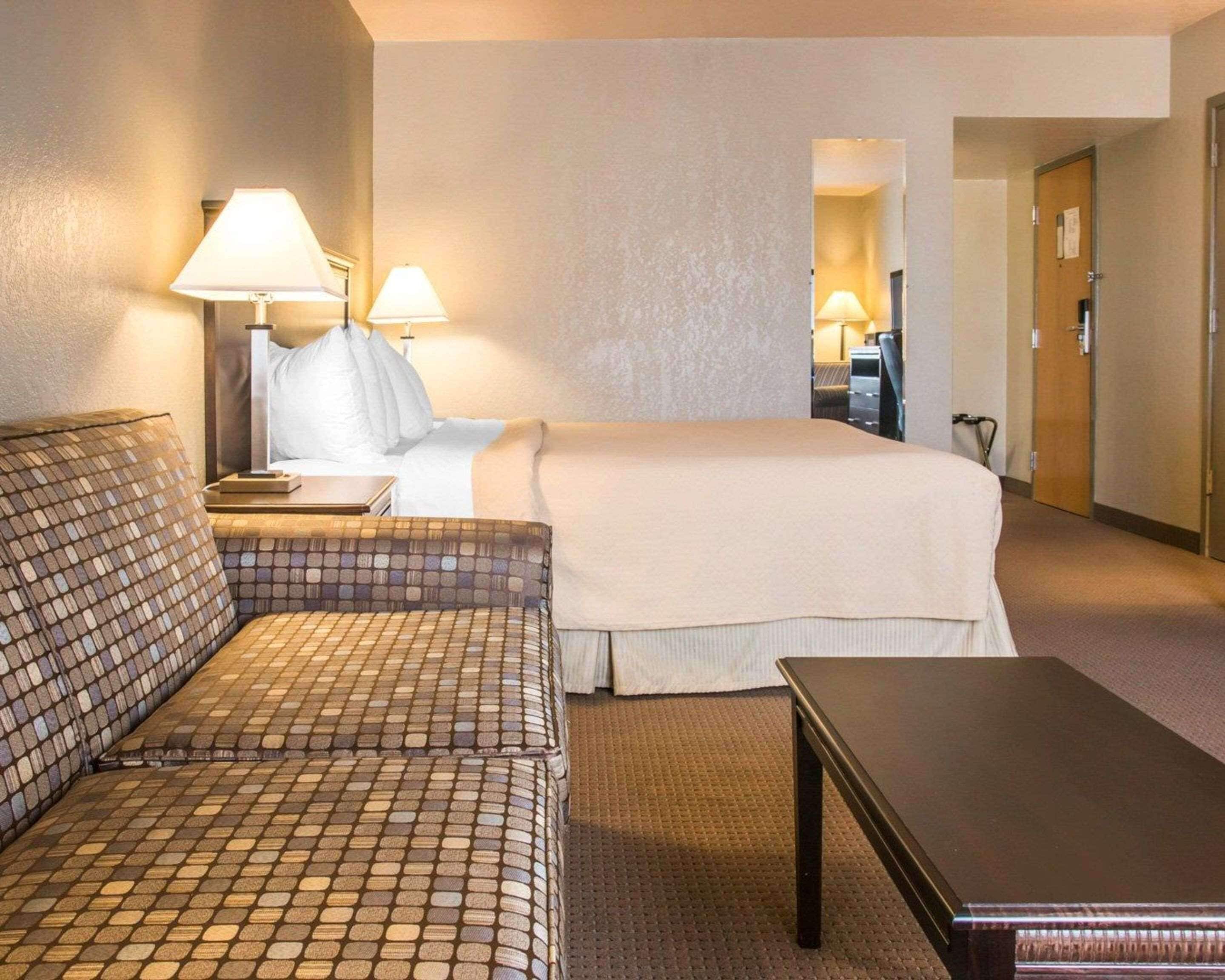 Una habitación de hotel con una cama, un sofá, una mesa y dos lámparas.
