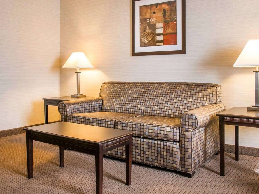 Ett hotellrum med en soffa i rutmönster, två sidobord och en inramad abstrakt målning på väggen.