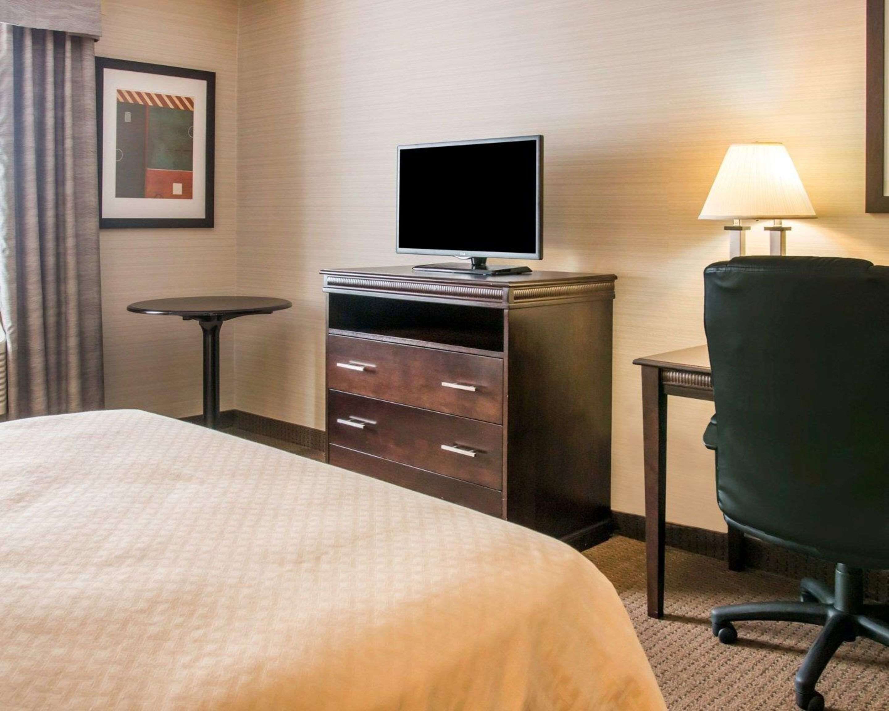 Ein Hotelzimmer mit Bett, Schreibtisch mit Fernseher, Stuhl und kleinem Tisch.