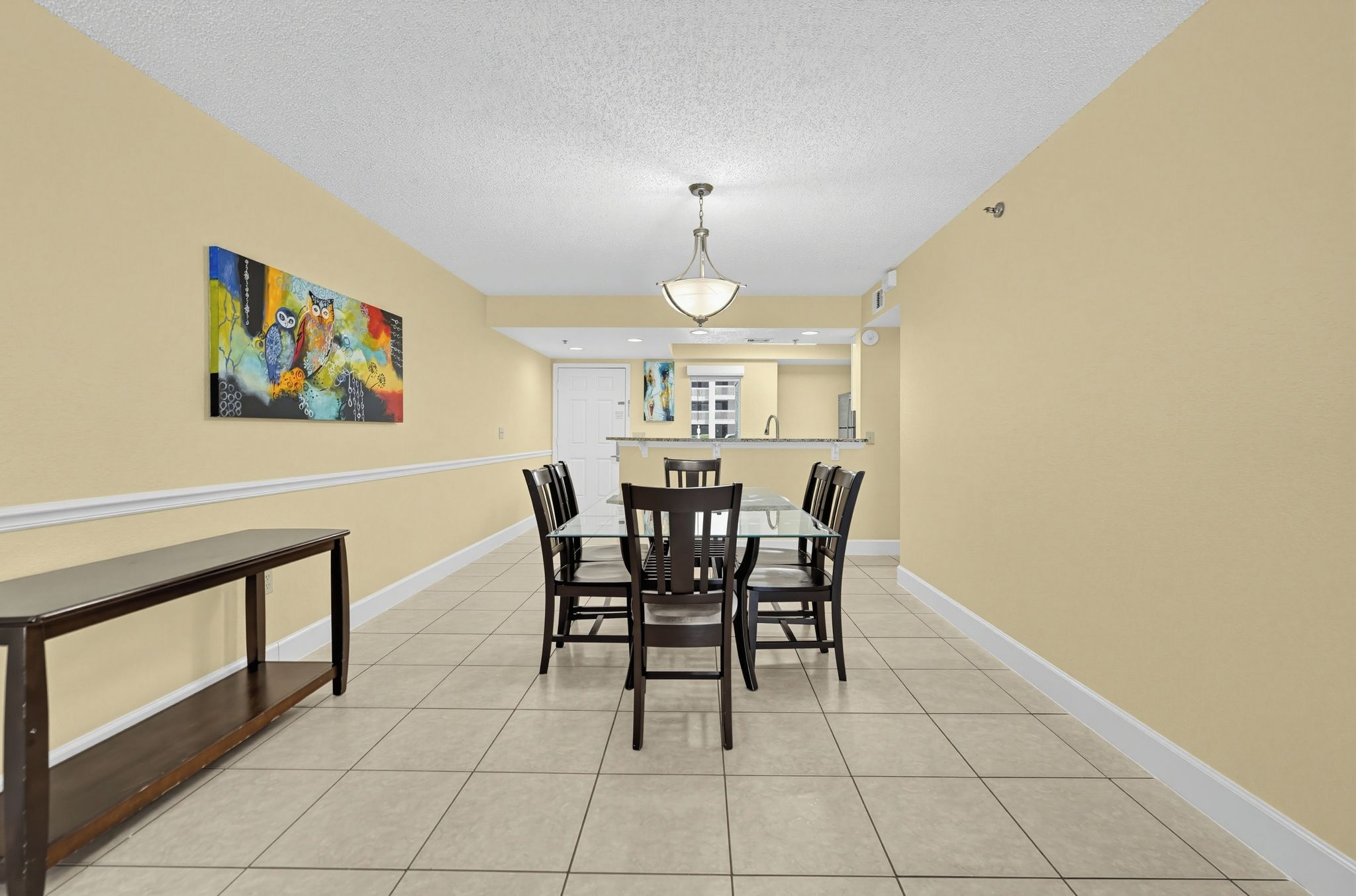 A dining area with a table and chairs, a bench, and a kitchen in the background.
