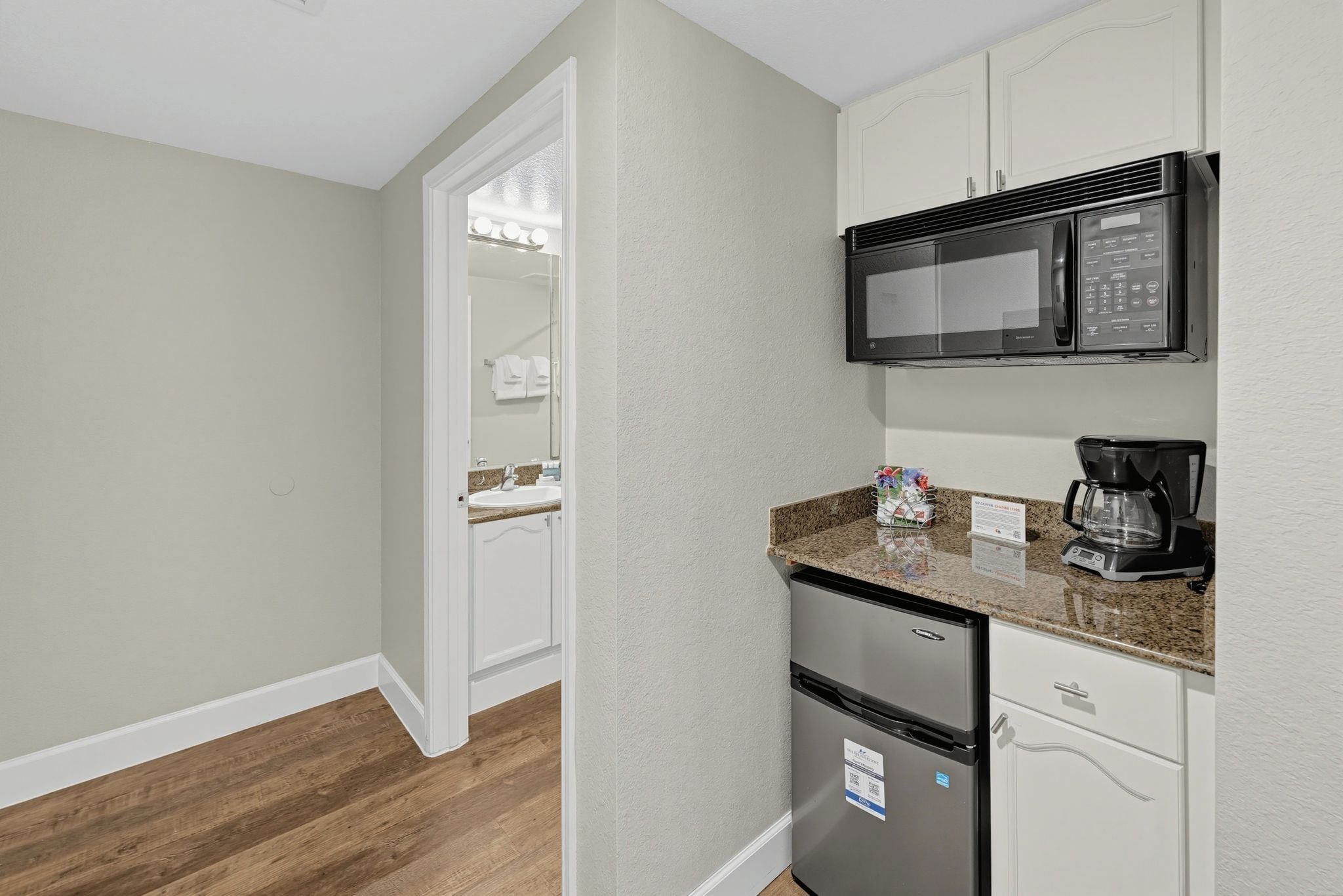 A compact kitchenette with a microwave, coffee maker, and refrigerator.