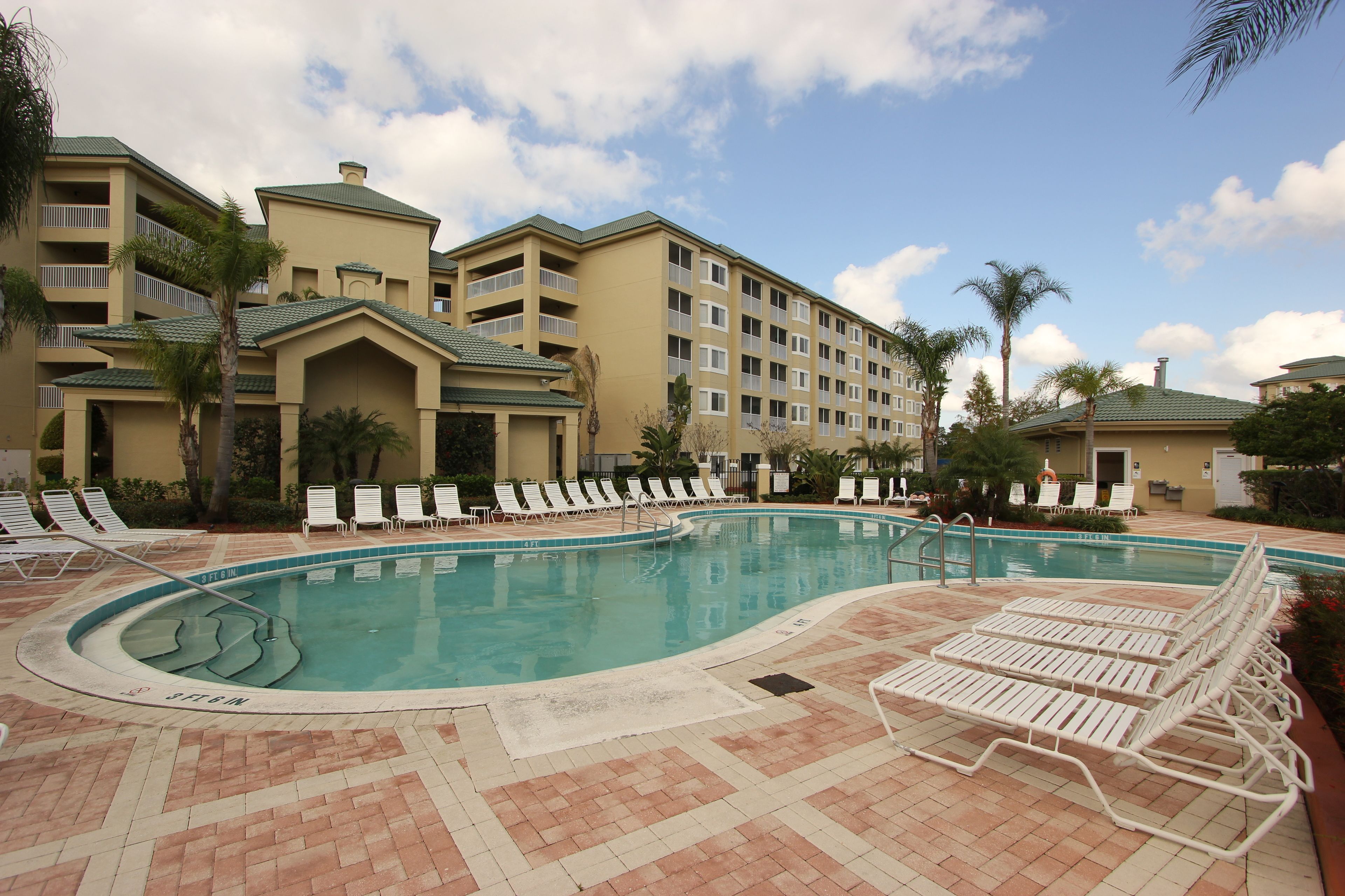 A hotel pool area with lounge chairs and a large pool.