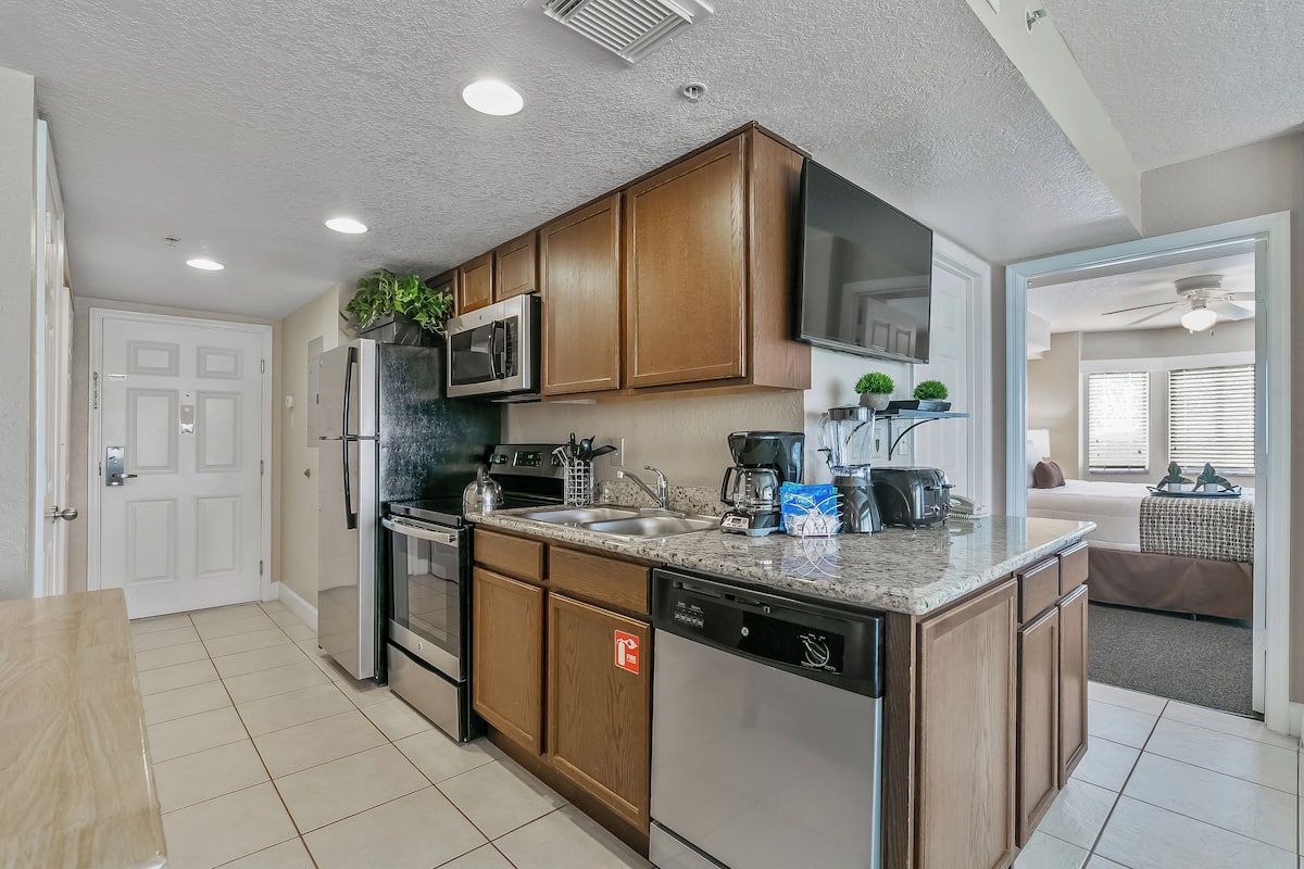 A modern kitchen with wooden cabinets, stainless steel appliances, and a granite countertop.