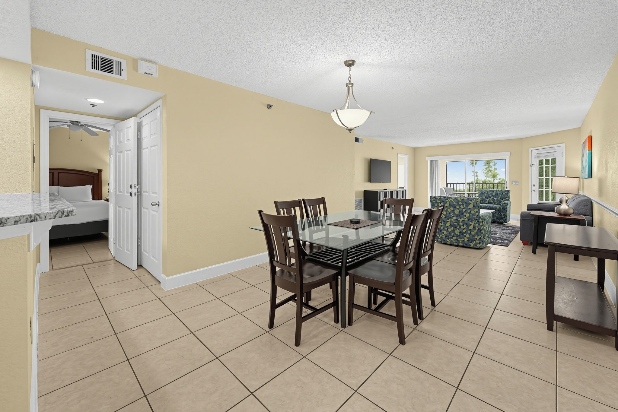 A spacious living area with a dining table, chairs, a sofa, and a TV.