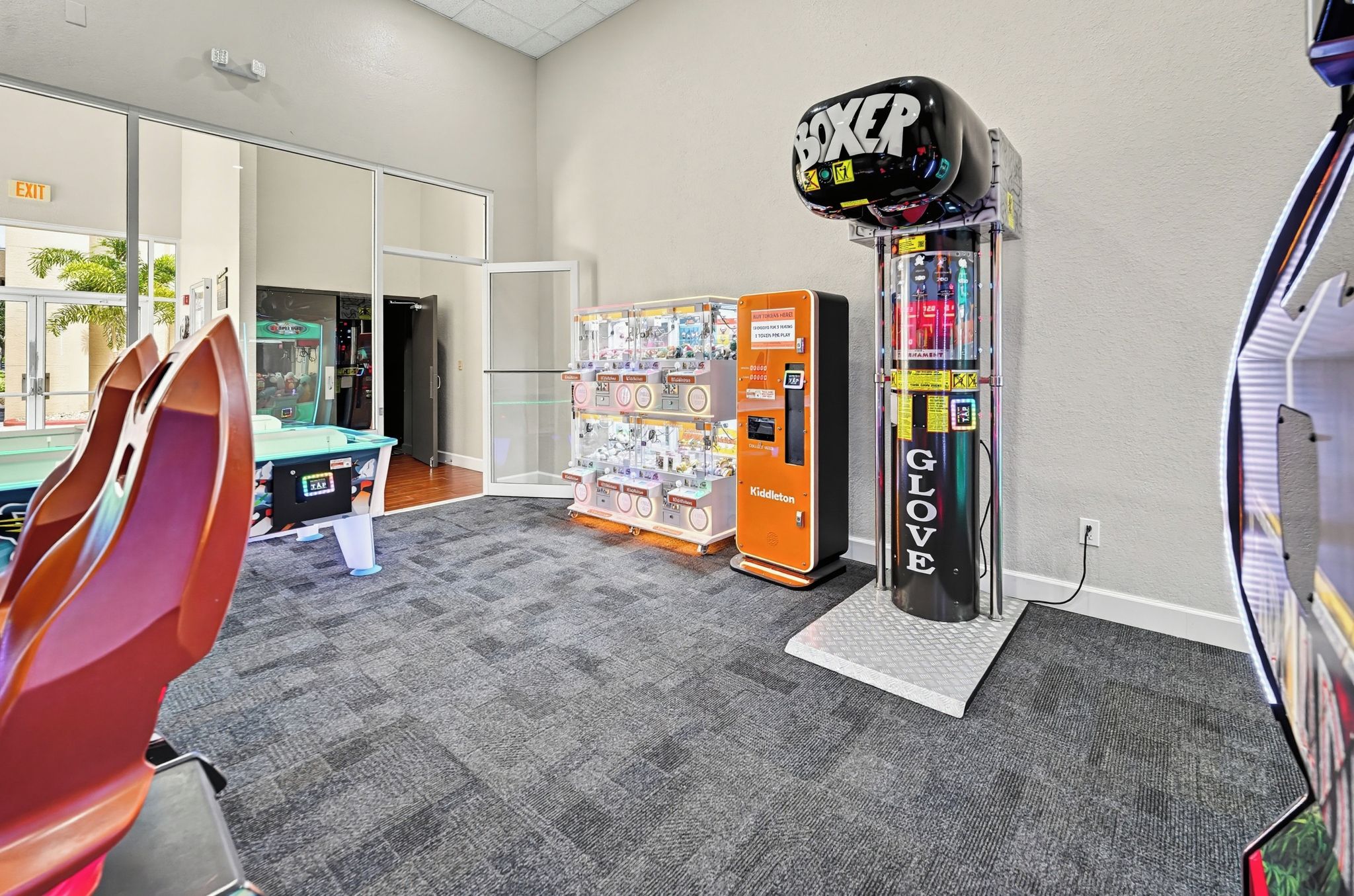 A room with a vending machine, a punching bag, and a glass door leading to another area.