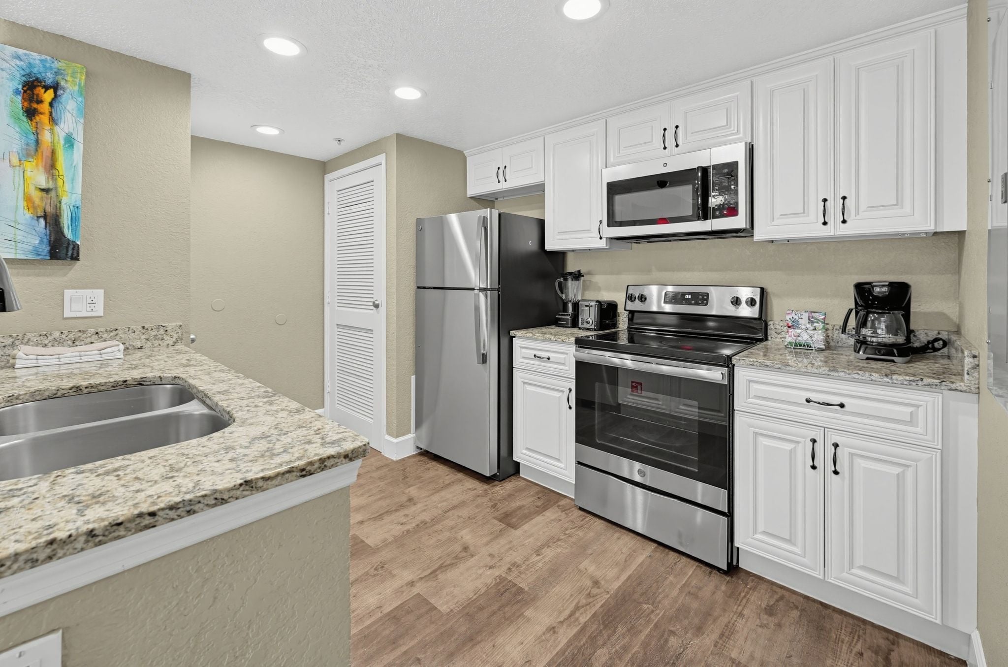 A kitchen with white cabinets, stainless steel appliances, and a granite countertop.