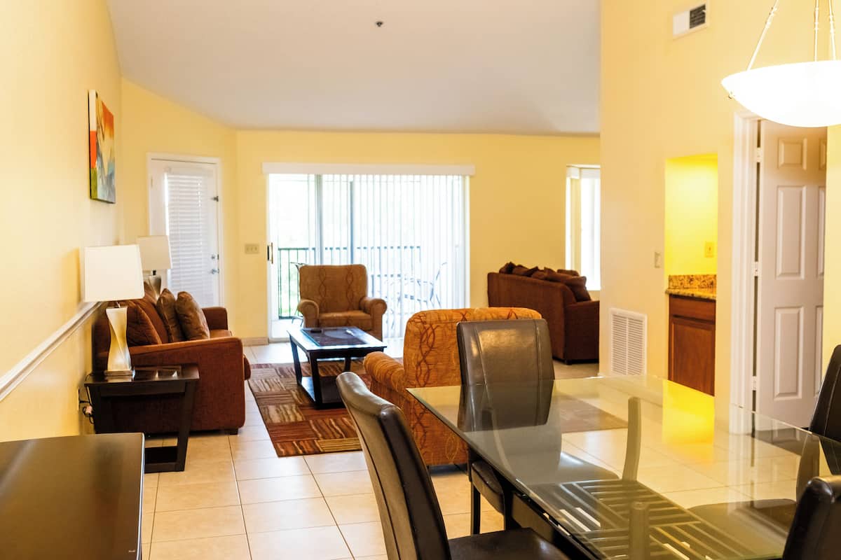 A living room with a glass dining table, two sofas, a coffee table, and a lamp.