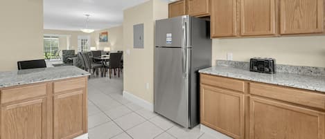 A modern kitchen with wooden cabinets, a stainless steel refrigerator, and a granite countertop.