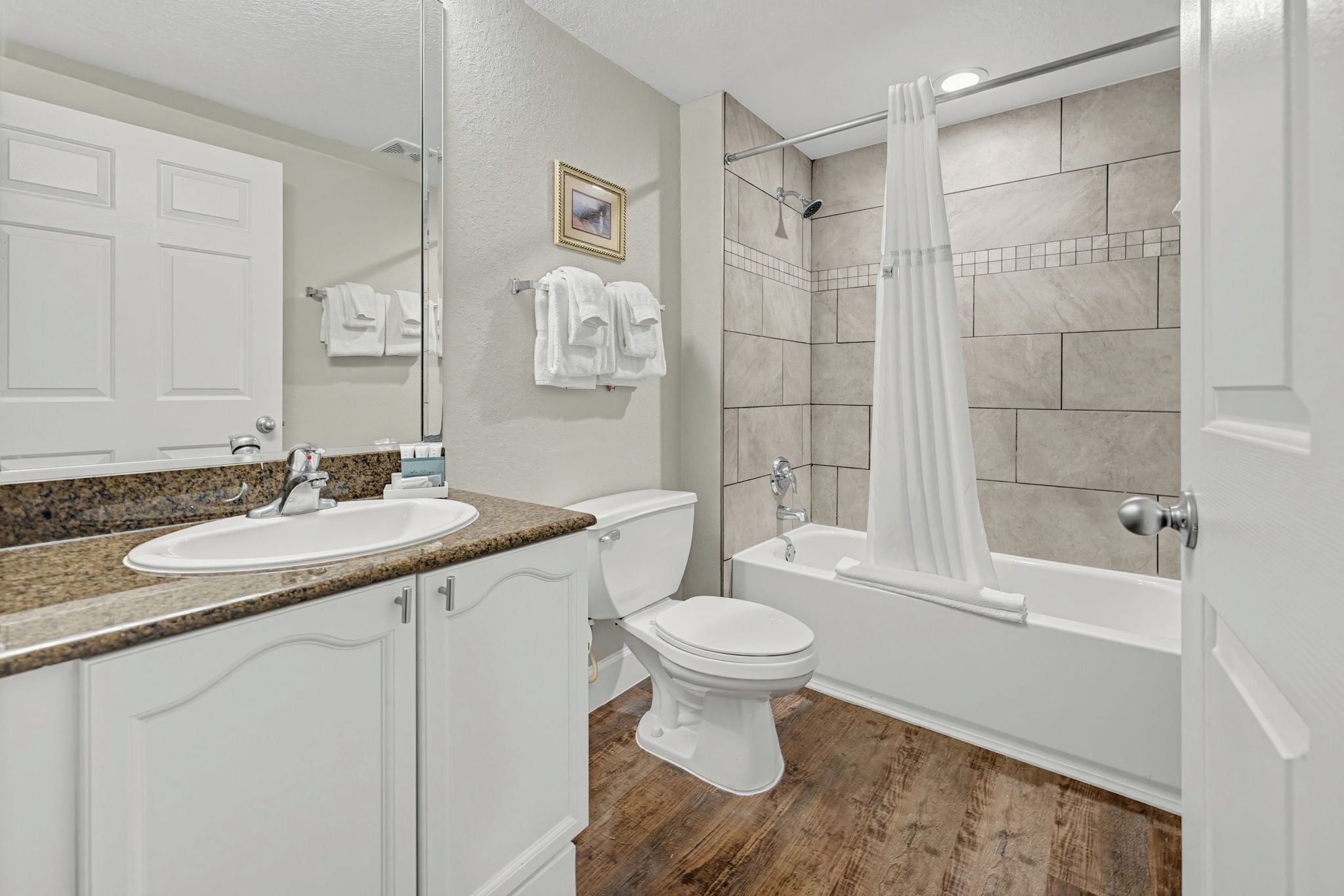 Une salle de bain équipée d’un lavabo, de toilettes, d’une baignoire et d’un rideau de douche.