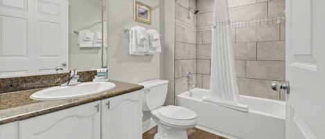 Une salle de bain équipée d’un lavabo, de toilettes, d’une baignoire et d’un rideau de douche.
