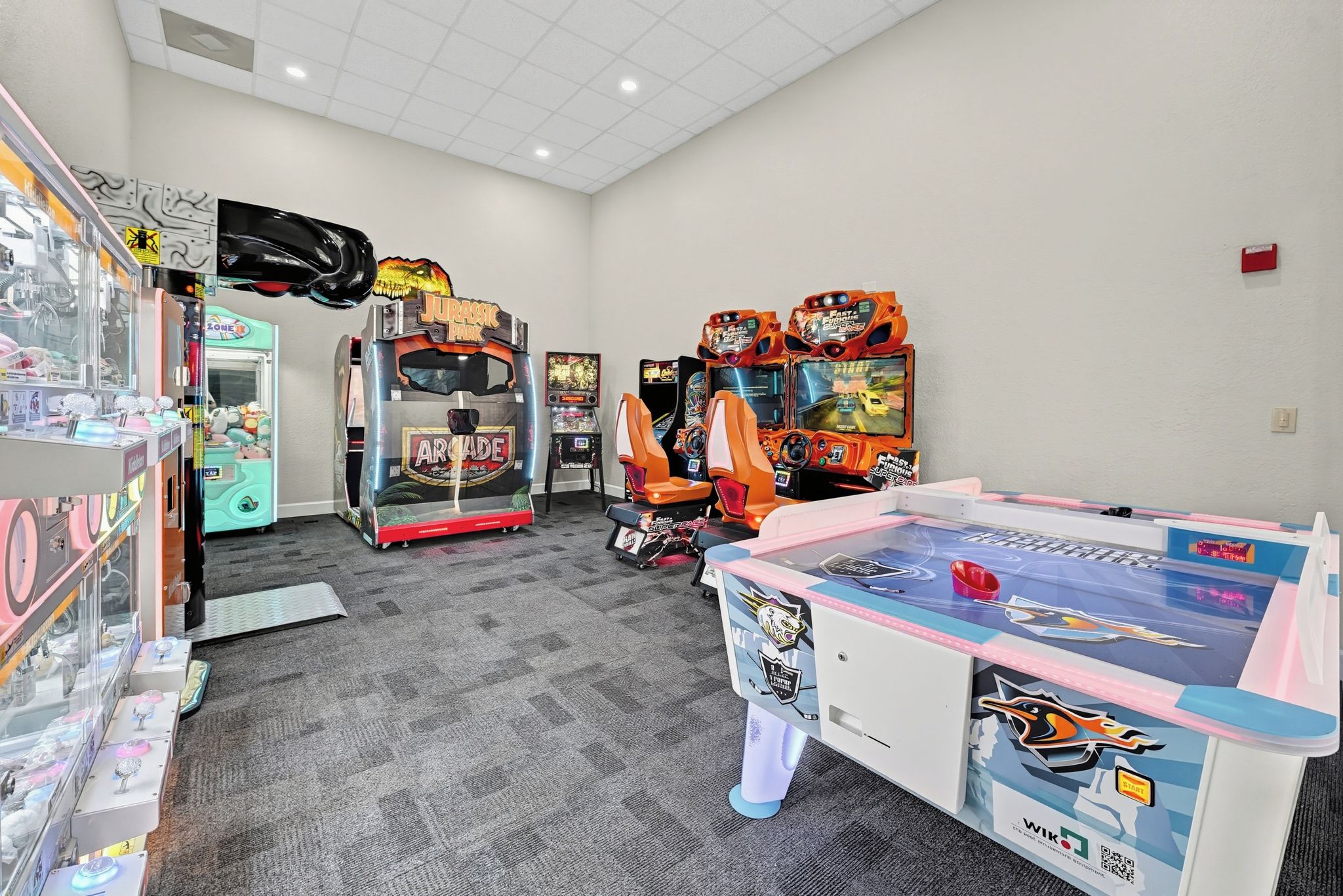 A room with arcade games, a ping pong table, and claw machines.
