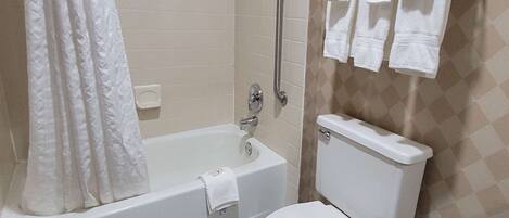 Un baño con bañera, inodoro y barras de apoyo.