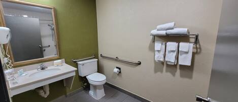 A bathroom with a sink, toilet, and hand dryer. There are towels on a rack.