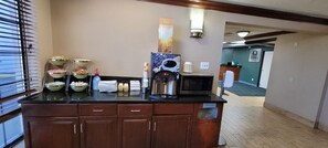 A kitchenette area with a coffee machine, microwave, and various food containers.