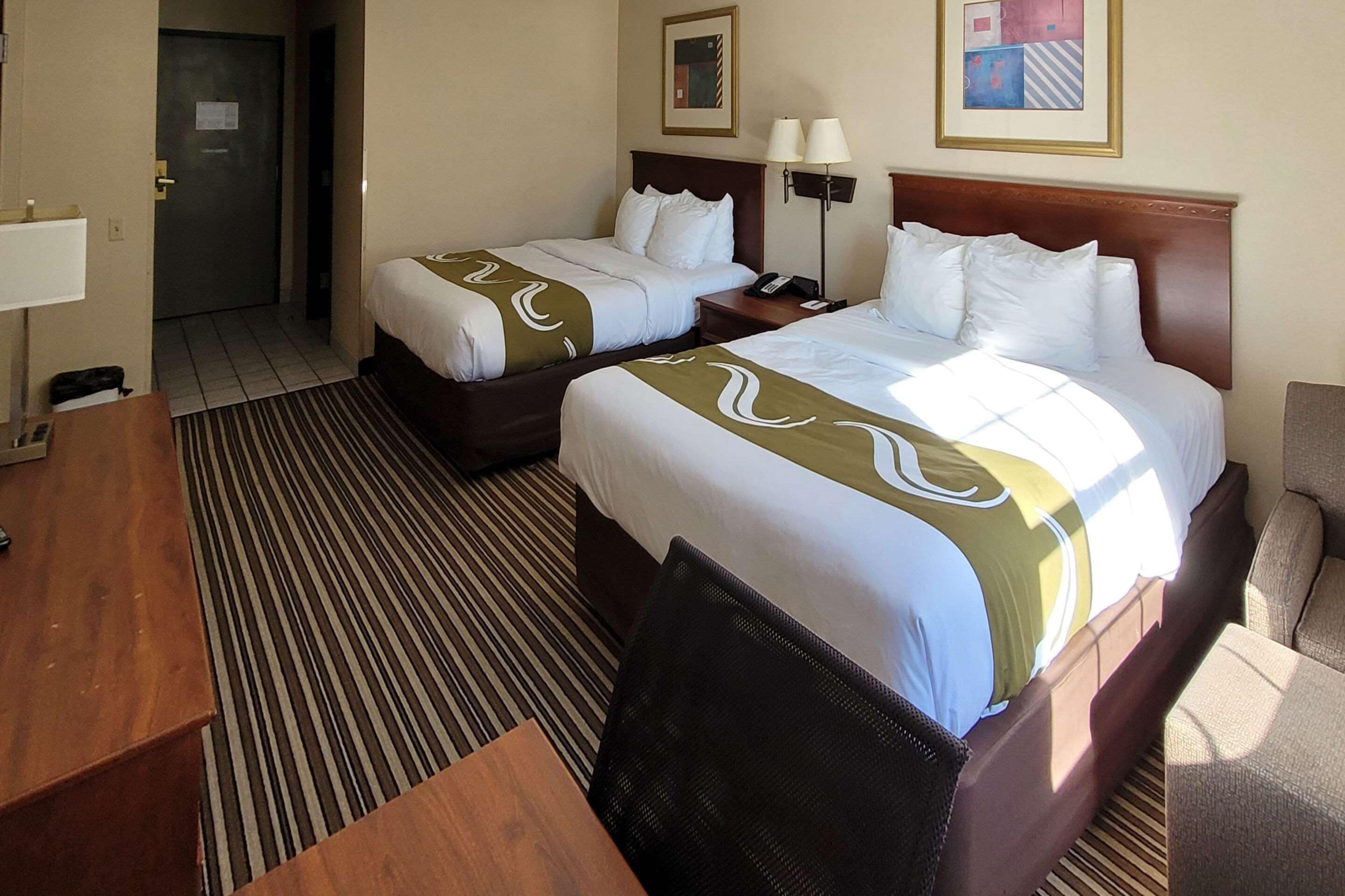 Habitación de hotel con dos camas, un escritorio y una silla.